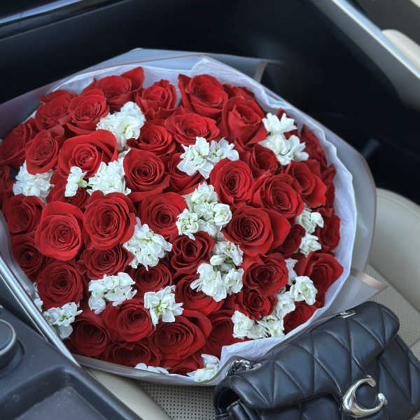 Large bouquet of red roses with small white flowers wrapped in white paper