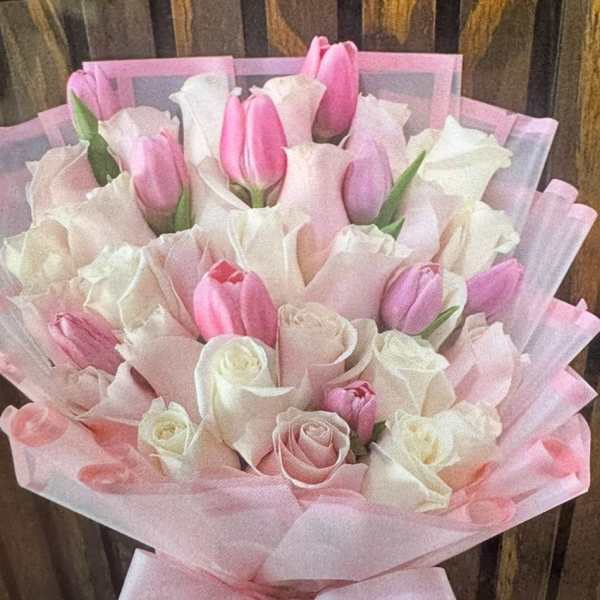 Pink and white tulip bouquet wrapped in pink paper with a bow