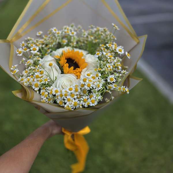 Bouquet of white daisies and roses with a sunflower center