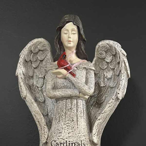 Angel figurine holding a red cardinal with yellow flowers at the base