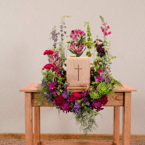 Floral wreath around a wooden cross on a table