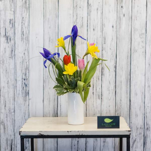Colorful tulips and irises arranged in a white vase
