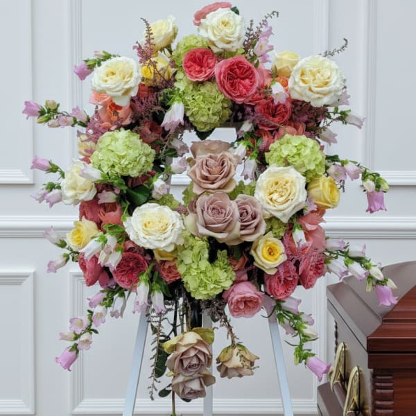 Large floral wreath on an easel beside a casket