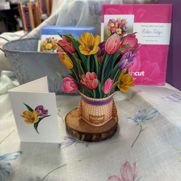 Colorful tulip bouquet in a woven basket with a greeting card