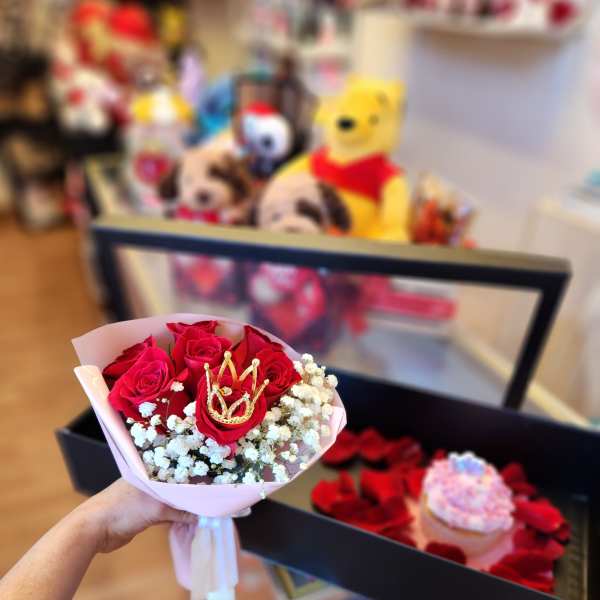 Handheld bouquet of red roses with white baby's breath and a gold crown pick