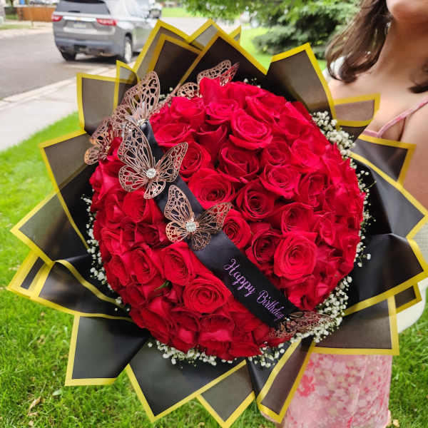 Large bouquet of red roses with butterfly decorations and a birthday ribbon