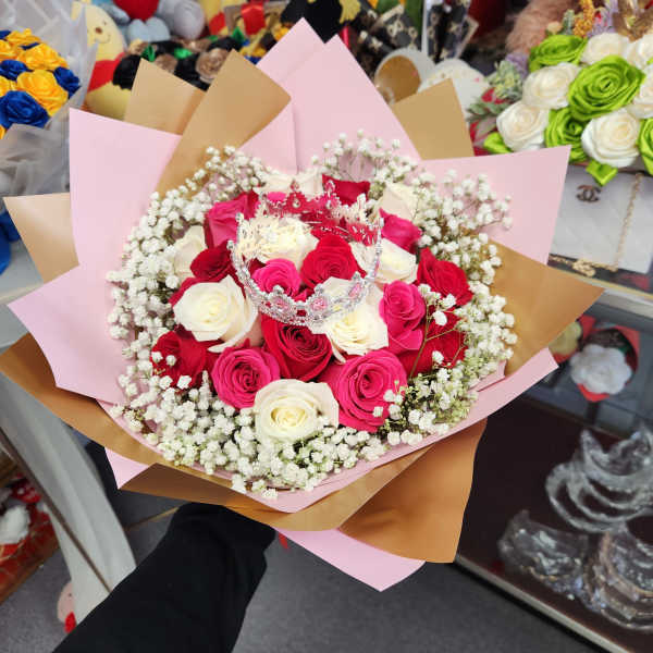 Bouquet of red, pink, and white roses with a small crown topper