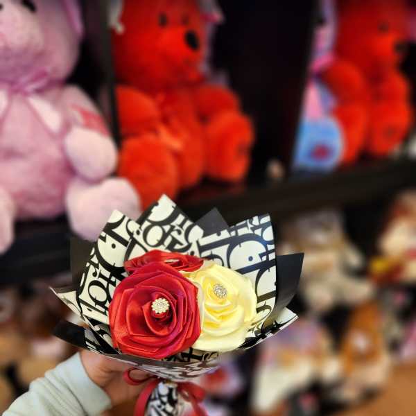 Small bouquet of red and cream roses wrapped in patterned paper