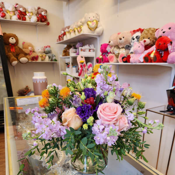 Mixed bouquet of pink, purple, and peach flowers in a glass vase
