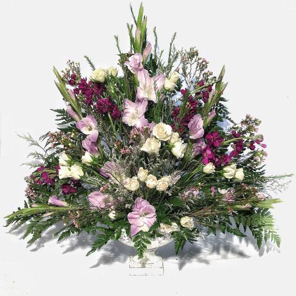 Fan-shaped arrangement of white spray roses and lavender flowers in a white pedestal bowl