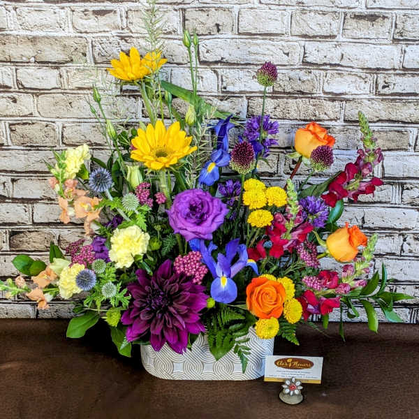 Colorful mixed flower arrangement in a patterned white container