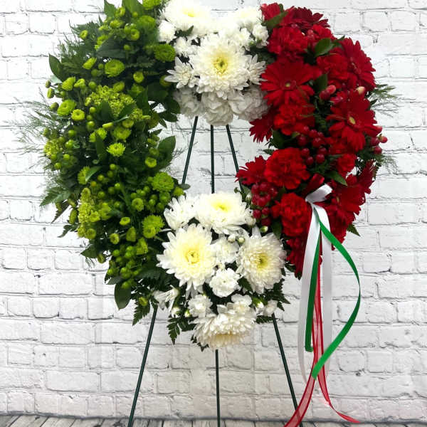 Heart-shaped floral wreath in red, white, and green on a stand