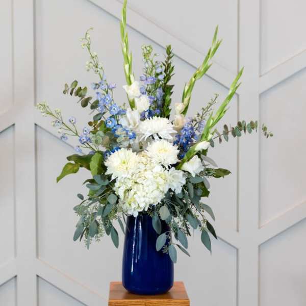 White and blue floral arrangement in a cobalt vase