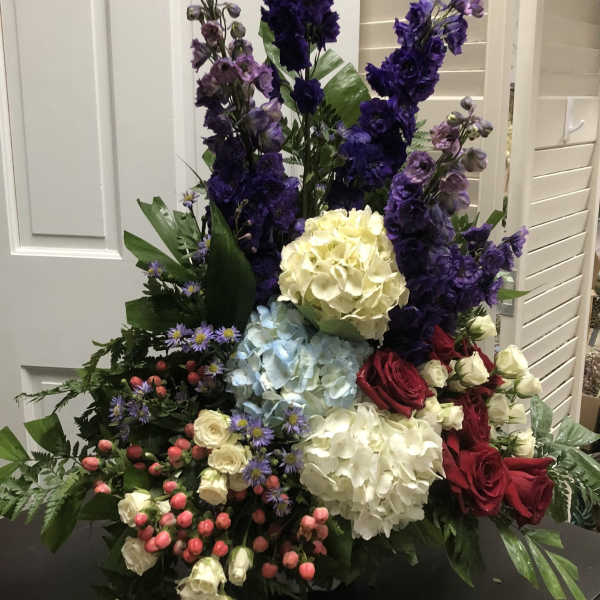 Tall mixed floral arrangement with purple, white, blue, and red blooms
