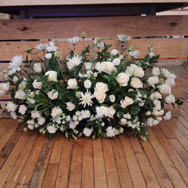 Large white floral arrangement with roses and daisy-like blooms