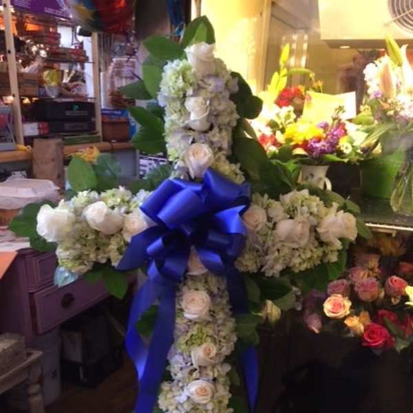 White floral cross with a blue ribbon bow