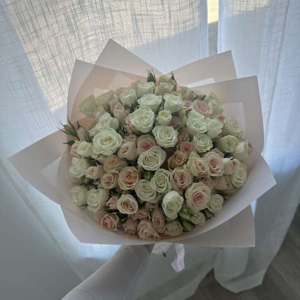Bouquet of pale pink and white roses wrapped in blush paper