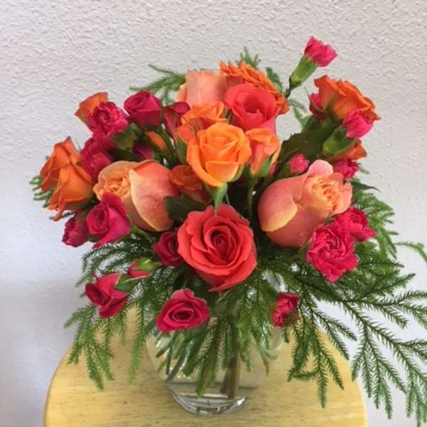 Bouquet of orange and pink roses in a clear glass vase