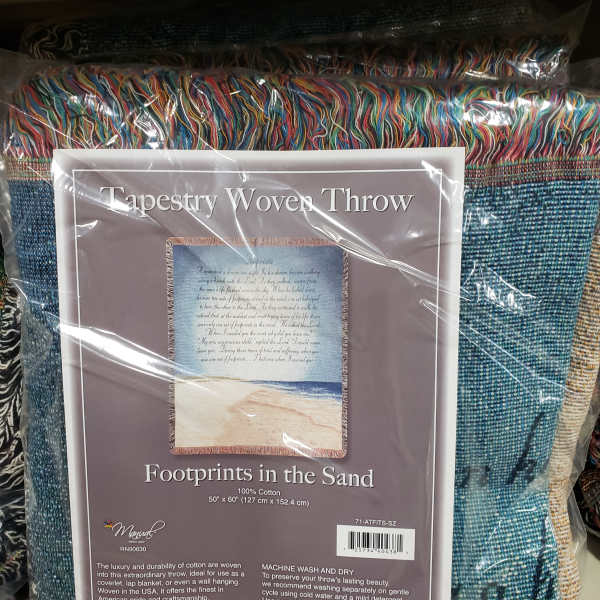 Packaged woven throw blanket with multicolored fringe and a beach scene label