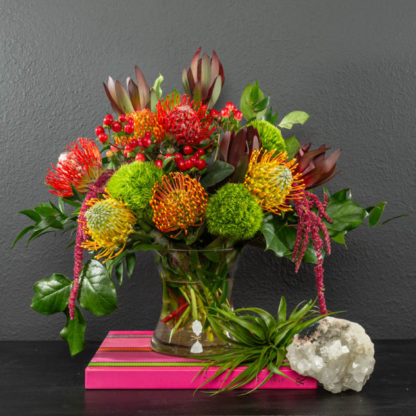 Colorful tropical bouquet in a glass vase with a small air plant