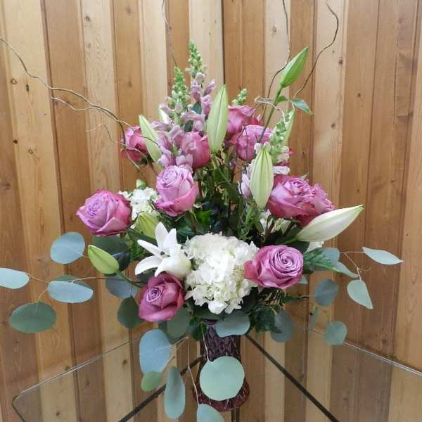 Pink roses and white lilies arranged in a vase with airy branches