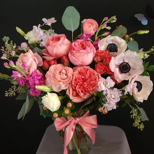 Pink and white bouquet in a glass vase with a satin ribbon