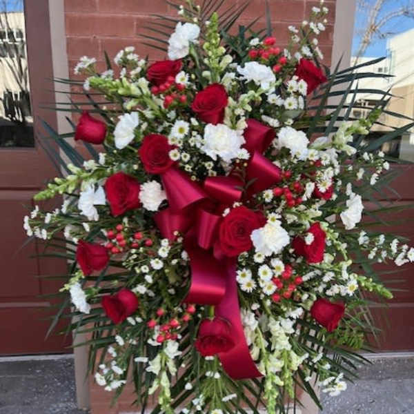 Large standing floral spray with red roses and white flowers on an easel
