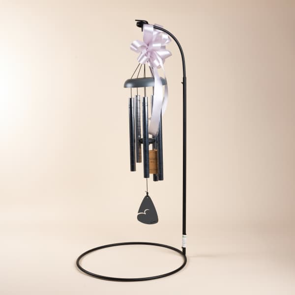Black wind chime with a pale ribbon bow and hanging tag