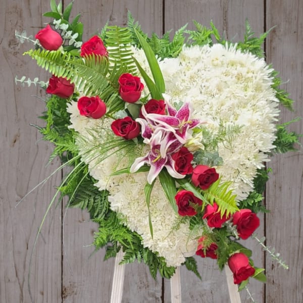 Heart-shaped floral spray with red roses and white blooms on a stand