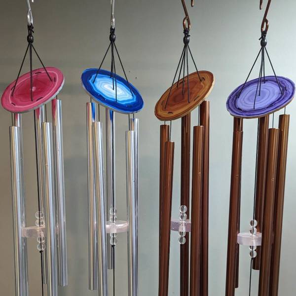 Four hanging wind chimes with colorful agate-style tops and metal tubes