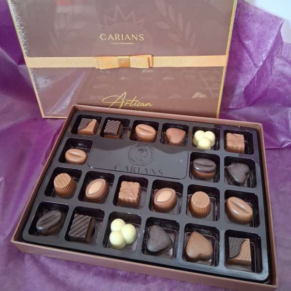 Box of assorted chocolates with a purple ribbon and tissue paper