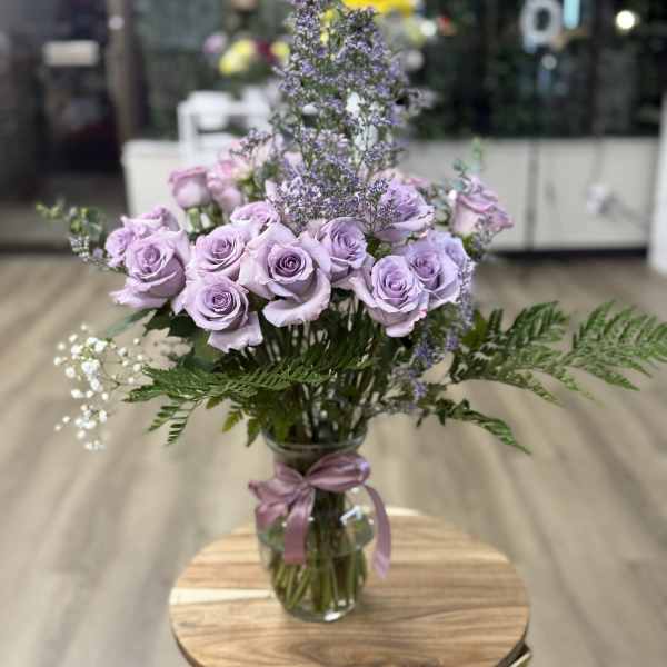Lavender roses in a glass vase with purple filler flowers
