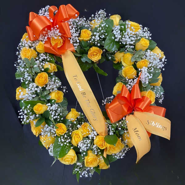 Heart-shaped wreath of yellow roses with orange ribbons on a dark background