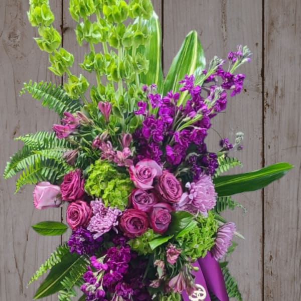 Tall standing floral spray with pink and purple flowers and a ribbon