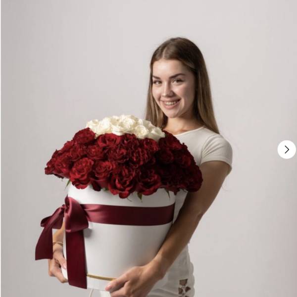 Woman holding a large box of red and white roses with a burgundy ribbon
