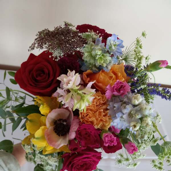 Handheld bouquet of mixed roses and colorful blooms