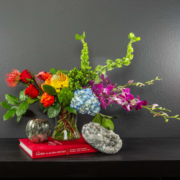 Colorful mixed bouquet in a glass vase with orchids and hydrangea