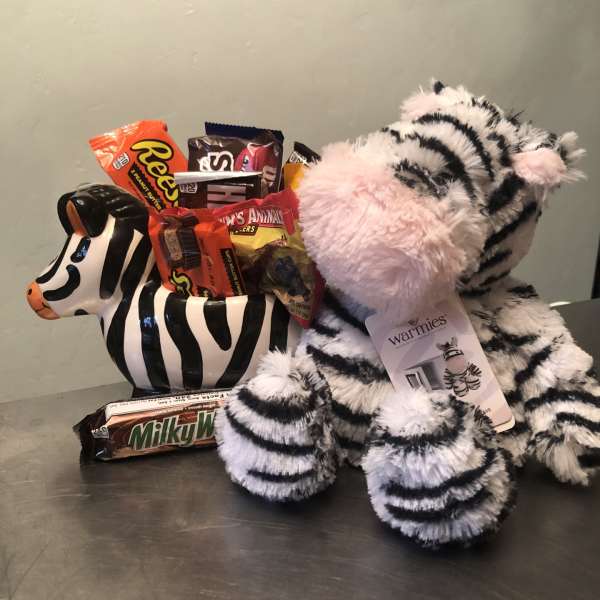 Zebra plush toy with assorted candy bars in a ceramic zebra container