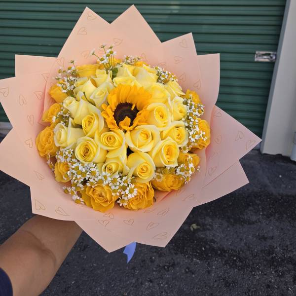 Yellow rose bouquet with a sunflower center in pink wrapping