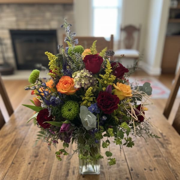 Mixed bouquet of roses and colorful flowers in a glass vase