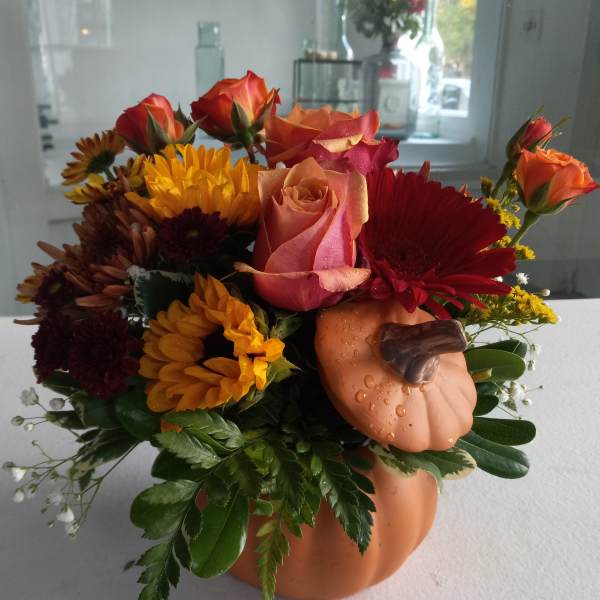 Autumn bouquet with roses, gerbera daisies, and a pumpkin container