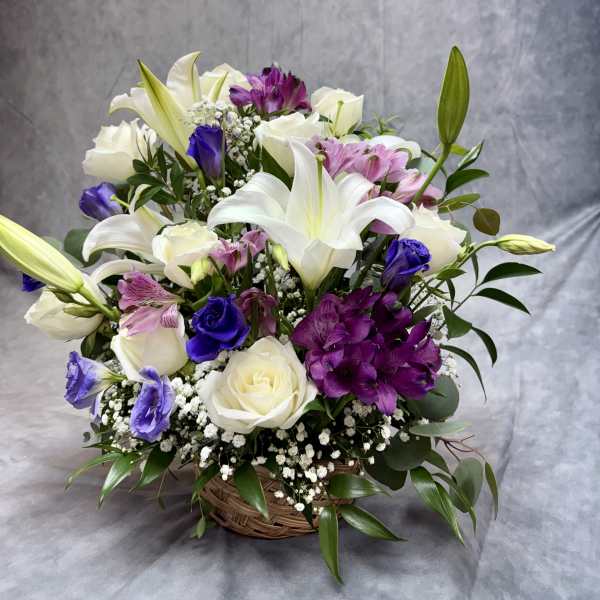 Basket arrangement of white lilies, roses, and purple flowers