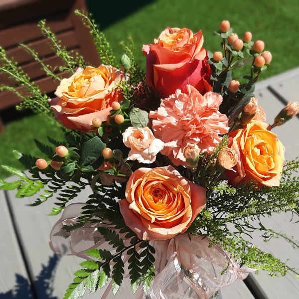 Bouquet of orange roses and peach carnations with greenery