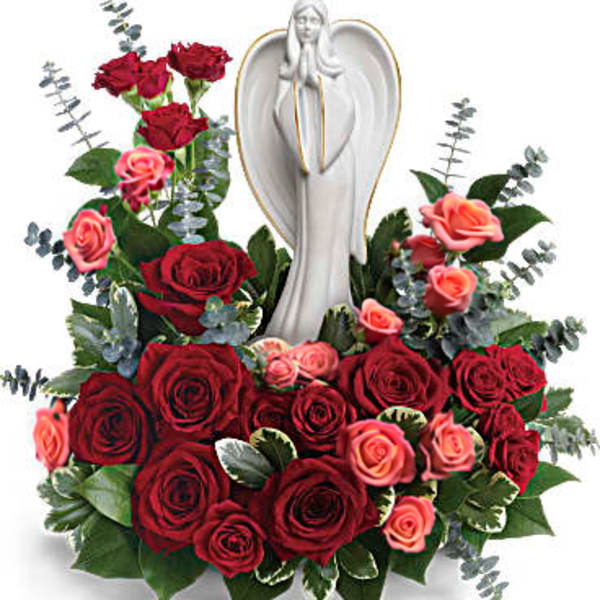 Red and pink roses arranged around a white angel figurine