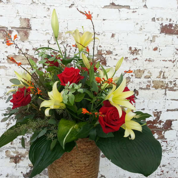 Red roses and yellow lilies in a woven basket