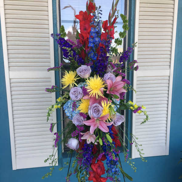 Tall standing floral spray with red, blue, purple, pink, and yellow blooms
