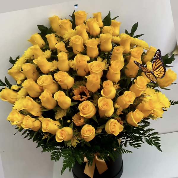 Yellow roses in a black hatbox with a butterfly accent