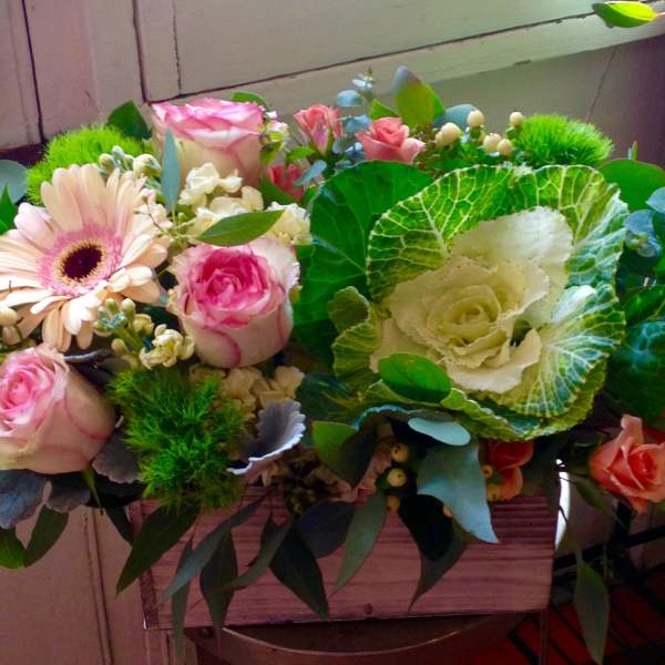 Mixed bouquet of pink roses, a gerbera daisy, and ornamental cabbage in a wooden box