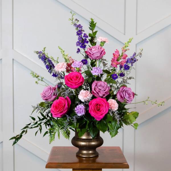 Pink and purple rose arrangement in a bronze vase