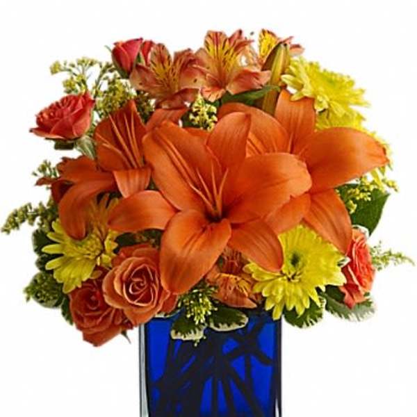 Orange and yellow flower arrangement in a blue glass vase